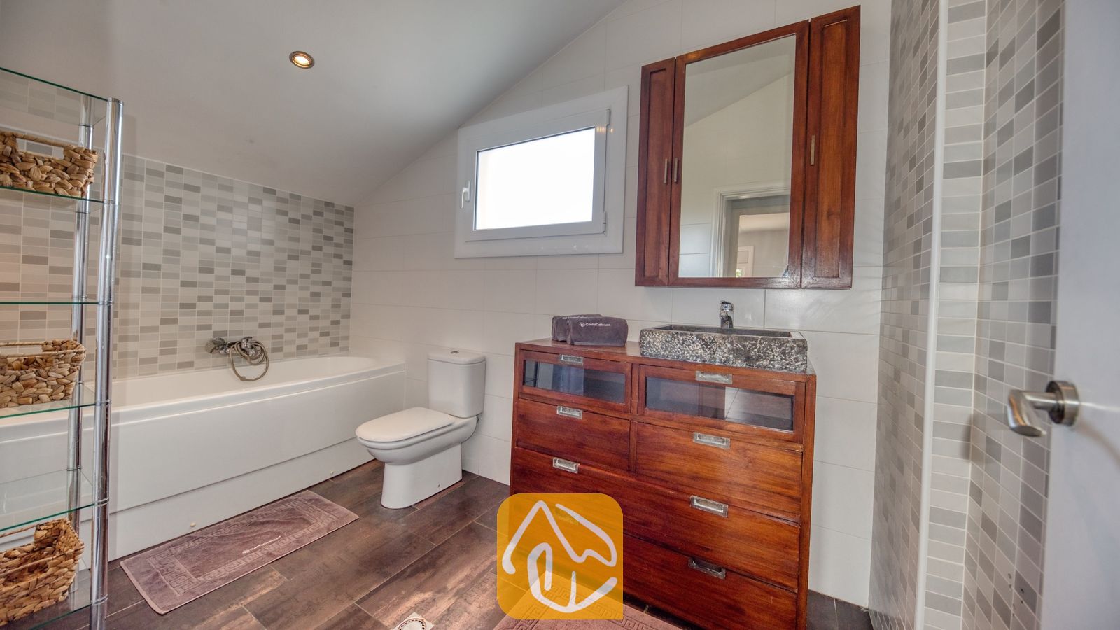 Moderne badkamer met een houten wastafelmeubel, een stenen waskom, een wit ligbad en grijze mozaïektegelaccenten.