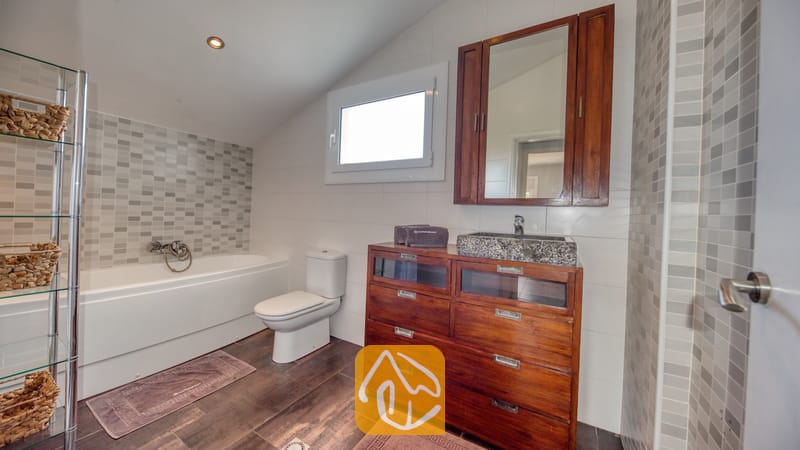 Moderne badkamer met een houten wastafelmeubel, een stenen waskom, een wit ligbad en grijze mozaïektegelaccenten.