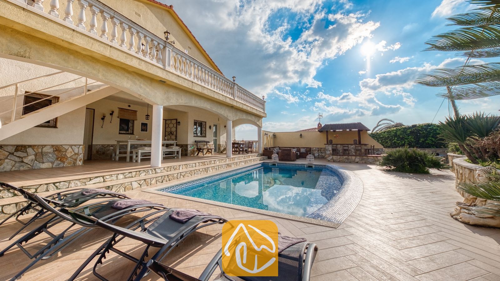 Privézwembad met ligstoelen op het betegelde terras van Villa Madonna in Spanje, voorzien van een overdekt terras en stenen muren onder een zonnige hemel