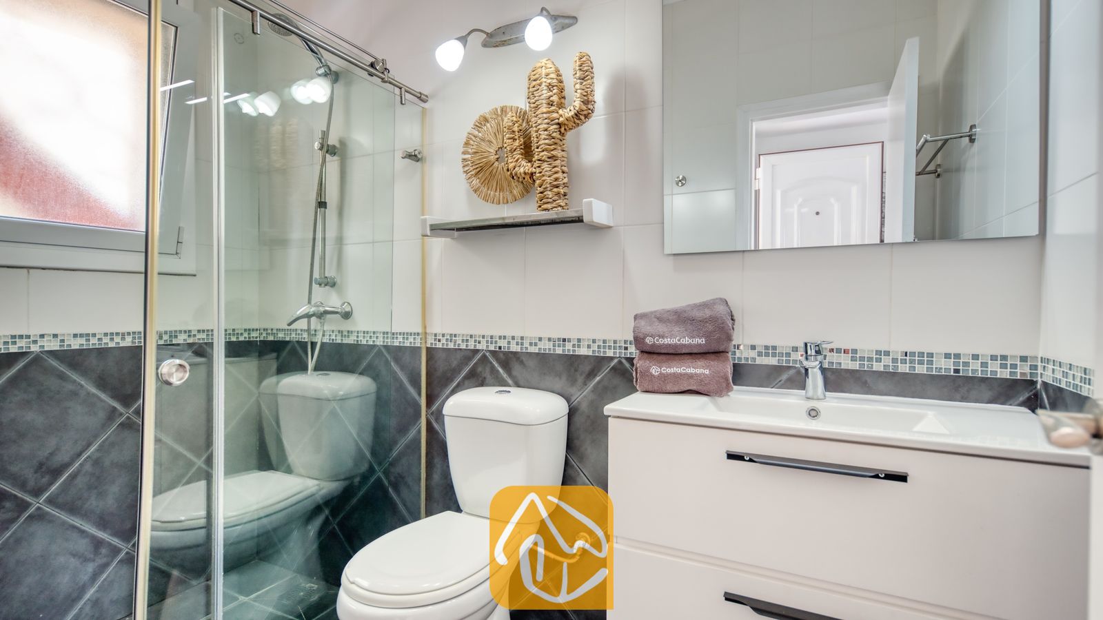 Moderne badkamer met een glazen douchecabine, een wit wastafelmeubel, toilet en geweven wanddecoratie.