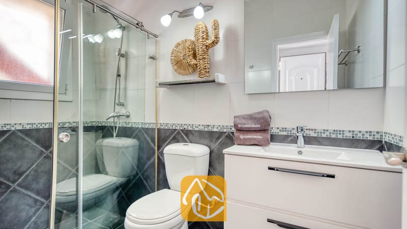 Moderne badkamer met een glazen douchecabine, een wit wastafelmeubel, toilet en geweven wanddecoratie.