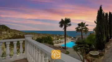 Terras met uitzicht op Villa Tropicana, voorzien van een eigen zwembad, palmbomen en zeezicht onder een roze en blauwe zonsondergang.