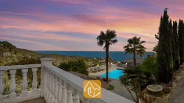 Terras met uitzicht op Villa Tropicana, voorzien van een eigen zwembad, palmbomen en zeezicht onder een roze en blauwe zonsondergang.