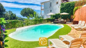 Privézwembad met ligstoelen en zitgelegenheid buiten bij Villa Sunny Beach in Spanje, voorzien van een groen gazon, witte zonneschermen en uitzicht op zee op de achtergrond.
